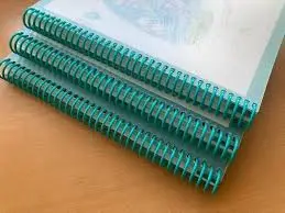 Tres documentos encuadernados con espiral de plástico color turquesa sobre una superficie de madera.