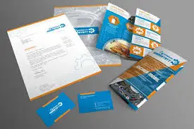 Conjunto de materiales de papelería corporativa con diseño profesional en tonos azul y naranja, incluyendo folletos, tarjetas de presentación y hojas membretadas.