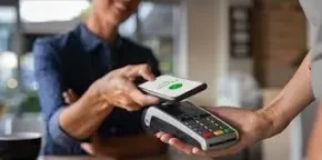 Persona realizando un pago sin contacto con su teléfono móvil en un terminal de punto de venta.